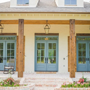 Immagine di un grande portico chic davanti casa con pavimentazioni in mattoni e un tetto a sbalzo