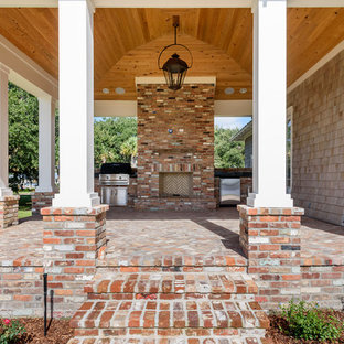 Immagine di un portico stile rurale di medie dimensioni e dietro casa con un focolare, pavimentazioni in mattoni e un tetto a sbalzo