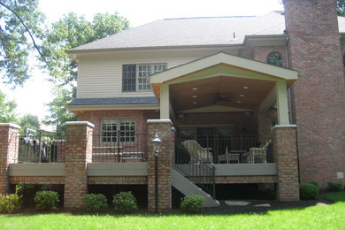 This is an example of a large traditional back porch design in Denver with a roof extension.