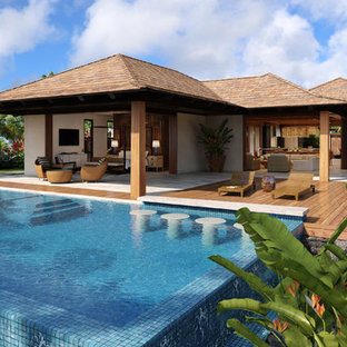 Foto di un ampio portico tropicale dietro casa con un focolare, piastrelle e un tetto a sbalzo
