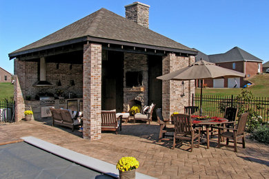 This is an example of a large traditional concrete paver porch design in St Louis with a roof extension.