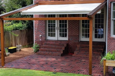 This is an example of a small traditional brick back porch design in Atlanta with a pergola.