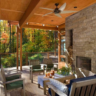 Immagine di un grande portico rustico dietro casa con un focolare, pedane e un tetto a sbalzo