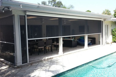 Large trendy concrete paver screened-in back porch photo in Orange County with a roof extension