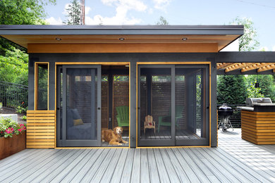 Mid-sized minimalist screened-in back porch idea in Minneapolis with decking and a roof extension