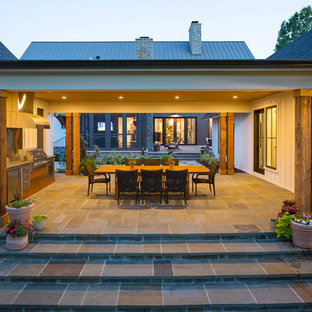 This is an example of a cottage stone porch design in Cincinnati with a roof extension.