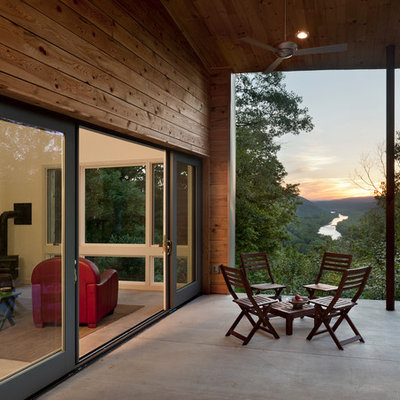 This is an example of a small contemporary concrete screened-in back porch design in DC Metro with a roof extension.
