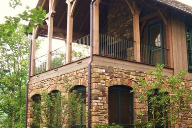 Cette photo montre un très grand porche d'entrée de maison latéral montagne avec un foyer extérieur, une terrasse en bois et une extension de toiture.