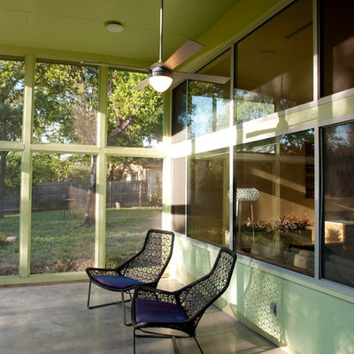 This is an example of a mid-sized contemporary concrete screened-in back porch design in Austin with a roof extension.