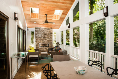 Cette photo montre un grand porche d'entrée de maison tendance avec une moustiquaire, une terrasse en bois et une extension de toiture.