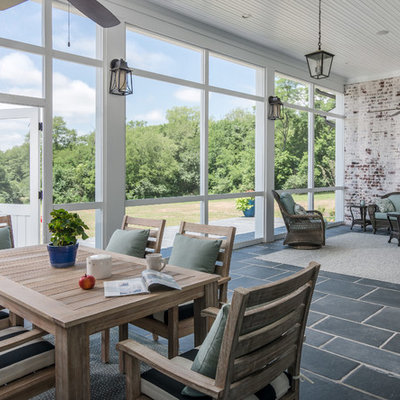 Farmhouse stone screened-in back porch idea in Nashville with a roof extension