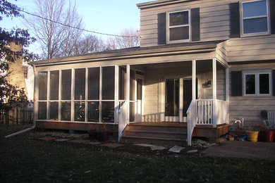 Imagen de porche cerrado de tamaño medio en patio trasero y anexo de casas con entablado