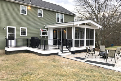 Inspiration for a large contemporary concrete paver screened-in back porch remodel in Boston with a roof extension