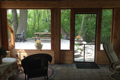 This is an example of a mid-sized back porch design in Minneapolis with a roof extension.