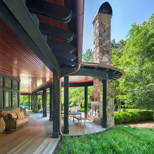 Idee per un ampio portico american style dietro casa con un focolare, pedane e un tetto a sbalzo