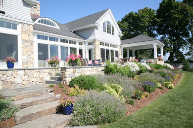 This is an example of a large craftsman stone back porch design in Boston.