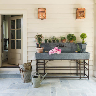 Foto di un portico country di medie dimensioni e dietro casa con un giardino in vaso, pavimentazioni in pietra naturale e un tetto a sbalzo