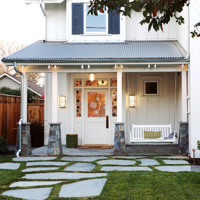 Mid-sized farmhouse stone front porch photo in Denver with a roof extension