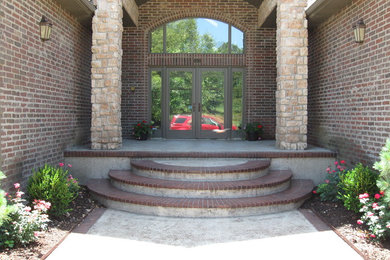 Immagine di un grande portico tradizionale davanti casa con cemento stampato e un tetto a sbalzo