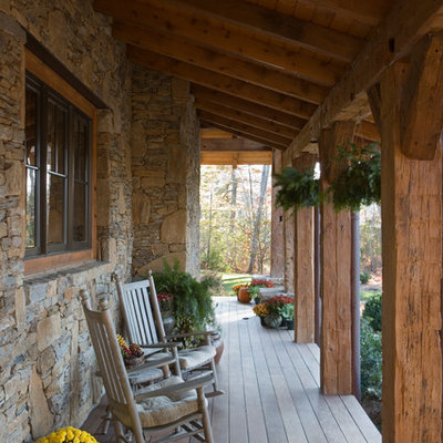 This is an example of a large rustic front porch design in Other with decking and a roof extension.