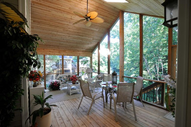 Cette image montre un grand porche d'entrée de maison arrière traditionnel avec une moustiquaire, une terrasse en bois et une extension de toiture.