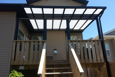 Small trendy back porch idea in Calgary with decking and a roof extension