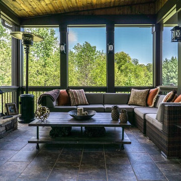 Tile floored screen porch with stone fireplace.