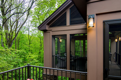 This is an example of a large transitional screened-in back porch design in Detroit with decking and a roof extension.