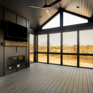 Immagine di un ampio portico classico dietro casa con un portico chiuso, pedane, un tetto a sbalzo e parapetto in legno