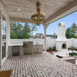 Design ideas for a large transitional backyard verandah in New Orleans with an outdoor kitchen, brick pavers and a roof extension.