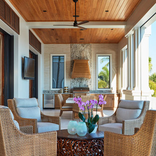 This is an example of a mid-sized tropical tile porch design in Miami with a roof extension.