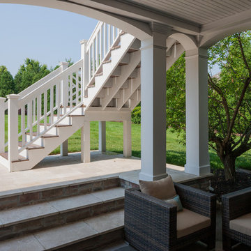 Two story double porch with outdoor fireplace, travertine patio, and AZEK deck