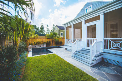Elegant stone screened-in back porch photo in New Orleans with a roof extension