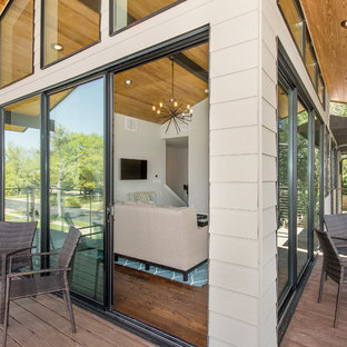 Ispirazione per un grande patio o portico moderno davanti casa con pedane e un tetto a sbalzo