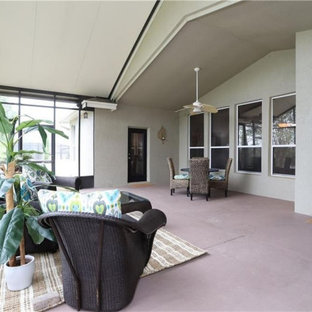 Immagine di un grande patio o portico chic dietro casa con un portico chiuso, lastre di cemento e un tetto a sbalzo