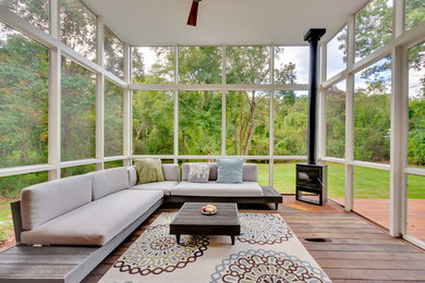 Réalisation d'un porche d'entrée de maison design avec une moustiquaire, une terrasse en bois et une extension de toiture.