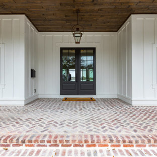 Esempio di un grande portico country davanti casa con pavimentazioni in mattoni e un tetto a sbalzo