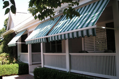 Exempel på en mellanstor modern veranda framför huset, med trädäck och markiser