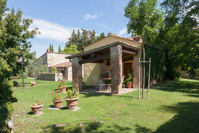 Ejemplo de porche cerrado de estilo de casa de campo pequeño en patio delantero con adoquines de piedra natural y pérgola