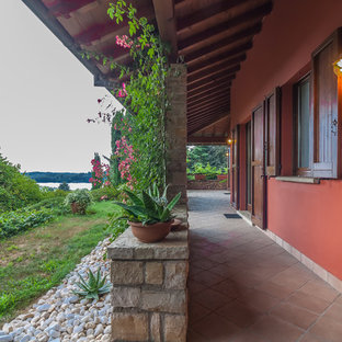 Immagine di un patio o portico mediterraneo davanti casa con piastrelle e un tetto a sbalzo