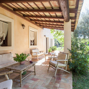 Immagine di un portico mediterraneo con pavimentazioni in mattoni e un parasole