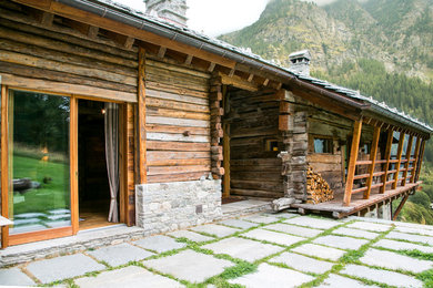 Réalisation d'un porche d'entrée de maison chalet avec des pavés en pierre naturelle et une extension de toiture.