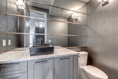 Inspiration for a medium sized contemporary cloakroom in Calgary with shaker cabinets, grey cabinets, a two-piece toilet, grey walls, medium hardwood flooring, a vessel sink, engineered stone worktops and brown floors.