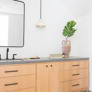Powder room - modern concrete floor and gray floor powder room idea in Los Angeles with flat-panel cabinets, light wood cabinets, white walls, an undermount sink and gray countertops