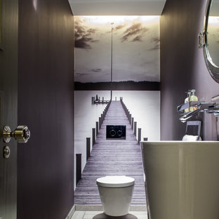 Imagen de aseo actual, de tamaño medio, con lavabo con pedestal, sanitario de pared y paredes púrpuras