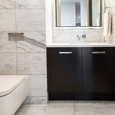 Example of a mid-sized minimalist white tile and marble tile marble floor and white floor powder room design in Vancouver with flat-panel cabinets, black cabinets, a wall-mount toilet, gray walls, an undermount sink, quartz countertops and white countertops