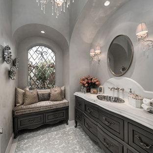 Réalisation d'un très grand WC et toilettes style shabby chic avec un placard à porte plane, des portes de placard marrons, un WC à poser, un carrelage multicolore, du carrelage en marbre, un mur beige, un sol en marbre, un lavabo encastré, un plan de toilette en quartz, un sol blanc et un plan de toilette multicolore.