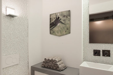 Example of a small trendy ceramic tile medium tone wood floor powder room design in Ottawa with flat-panel cabinets, white cabinets, a wall-mount toilet, white walls, a vessel sink and quartz countertops