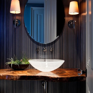 Cette photo montre un WC et toilettes exotique avec une vasque, un mur noir et un plan de toilette marron.