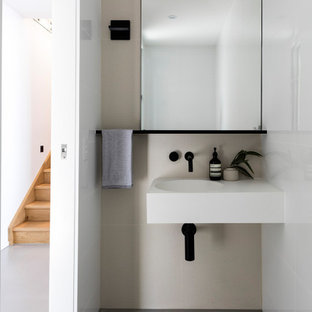 Design ideas for a modern powder room in Sunshine Coast with beige tile, concrete floors, an integrated sink, grey floor and white benchtops.